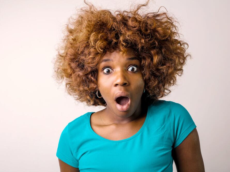 portrait photo of shocked woman in blue t shirt standing in front of white background